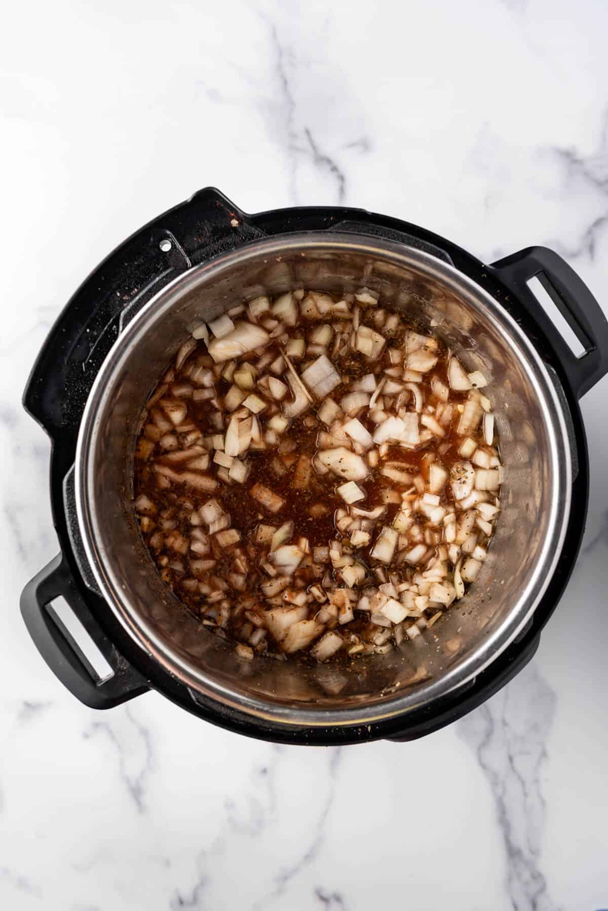 Adding chopped onions to an Instant Pot with other ingredients.
