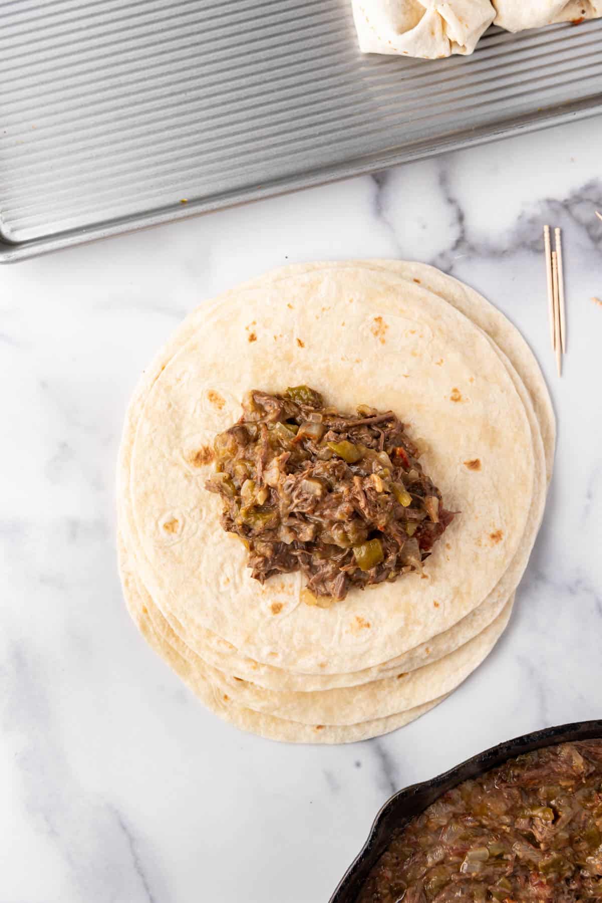 Shredded beef chimichanga filling on top of a tortilla.