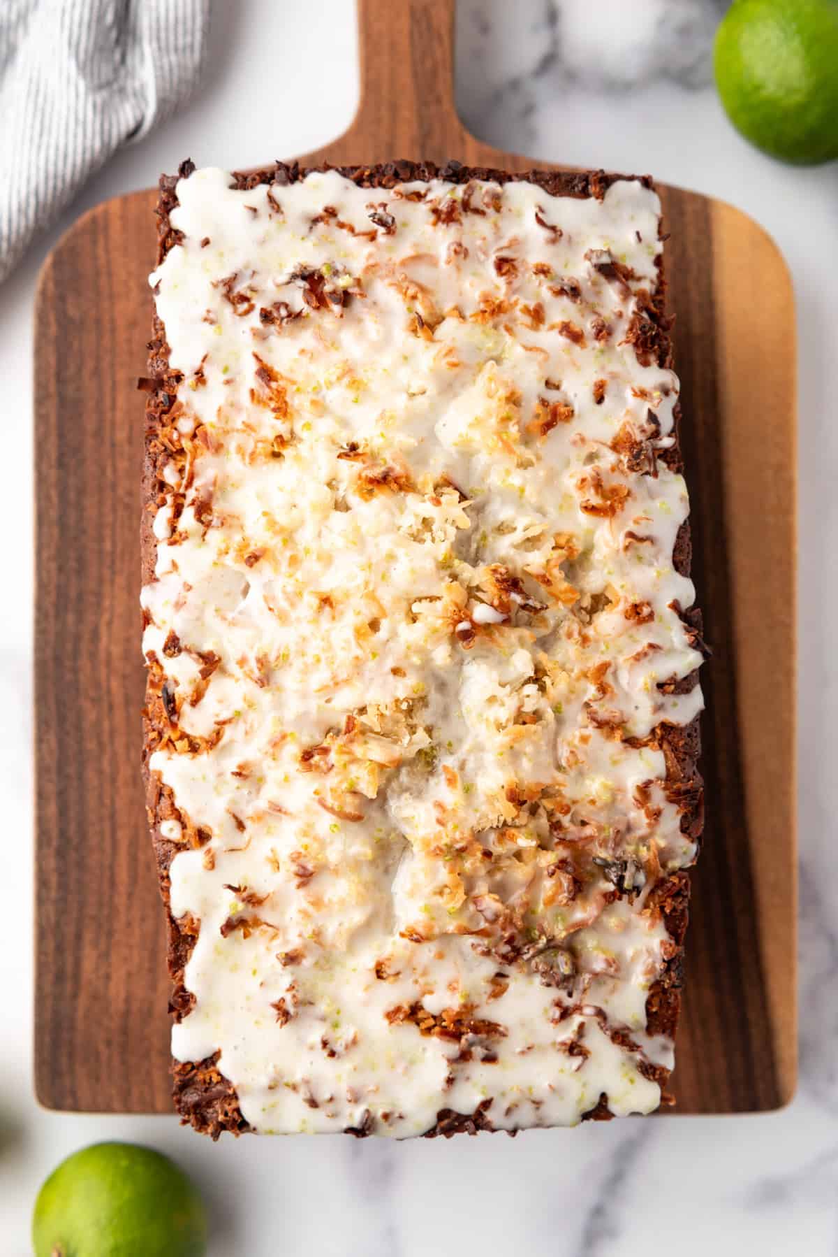 A loaf of coconut lime banana bread on a wooden cutting board.