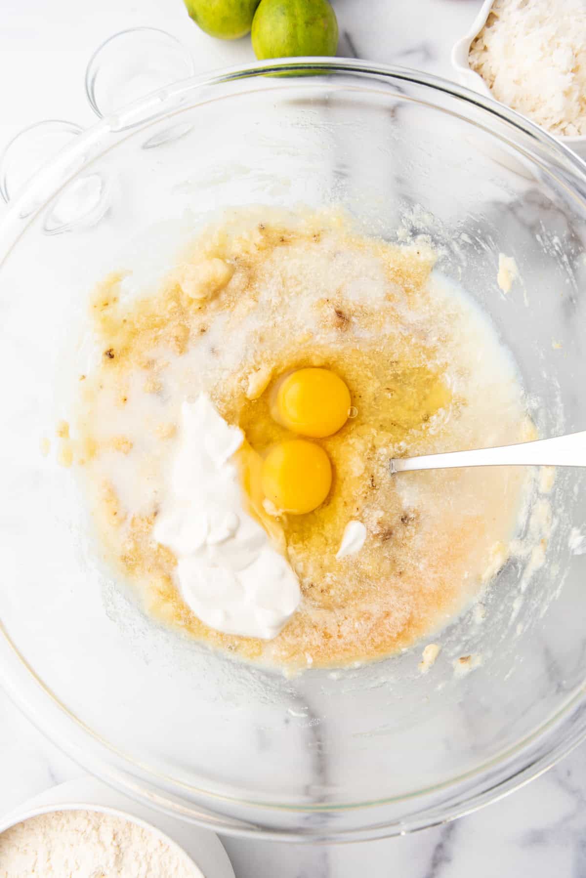 Adding sour cream, milk, and eggs to make banana bread.