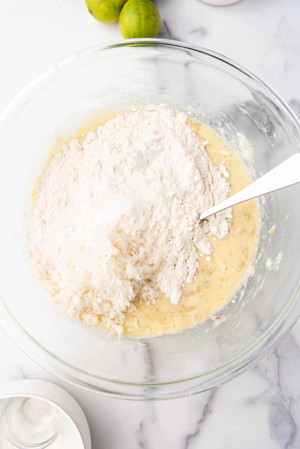 Adding dry ingredients to make banana bread.