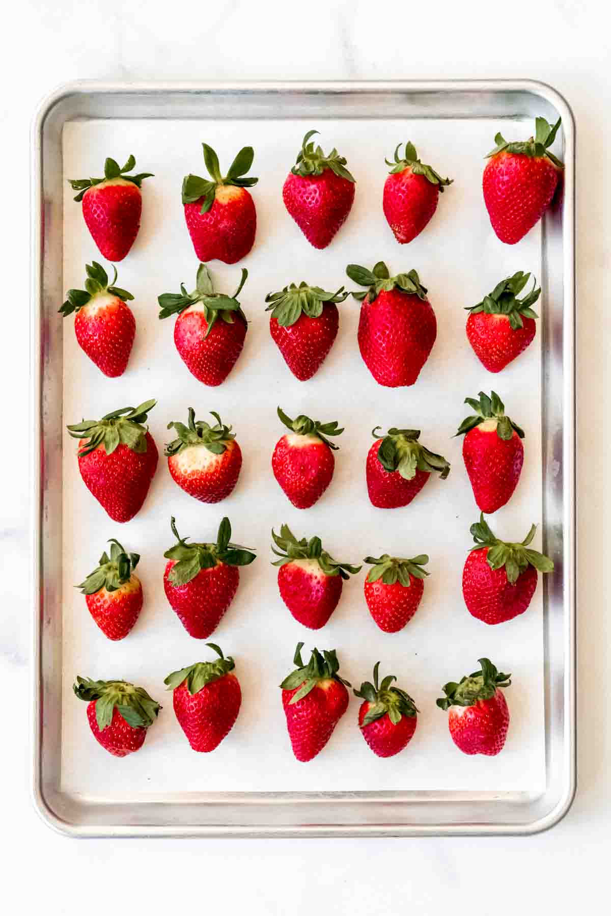 Washed strawberries lined up on a baking sheet.