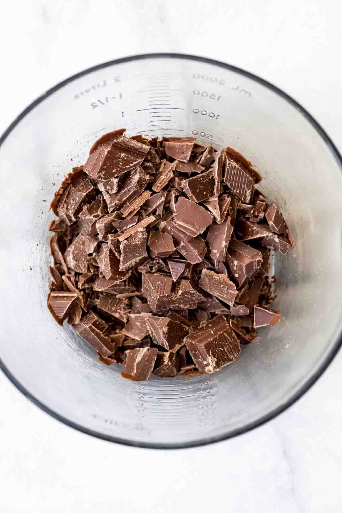 Chopped milk chocolate in a glass bowl.