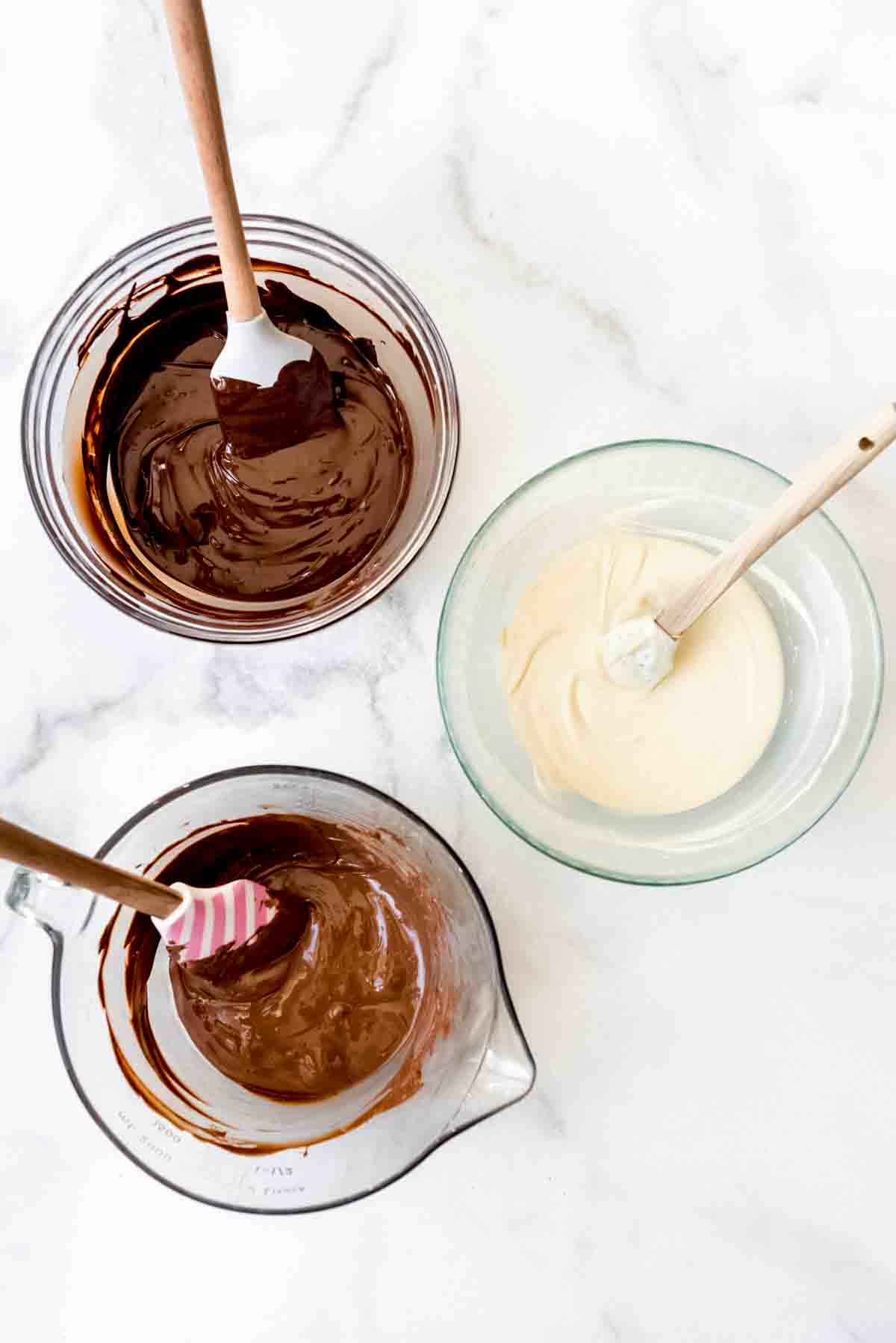 Three bowls of melted dark, white, and milk chocolate.