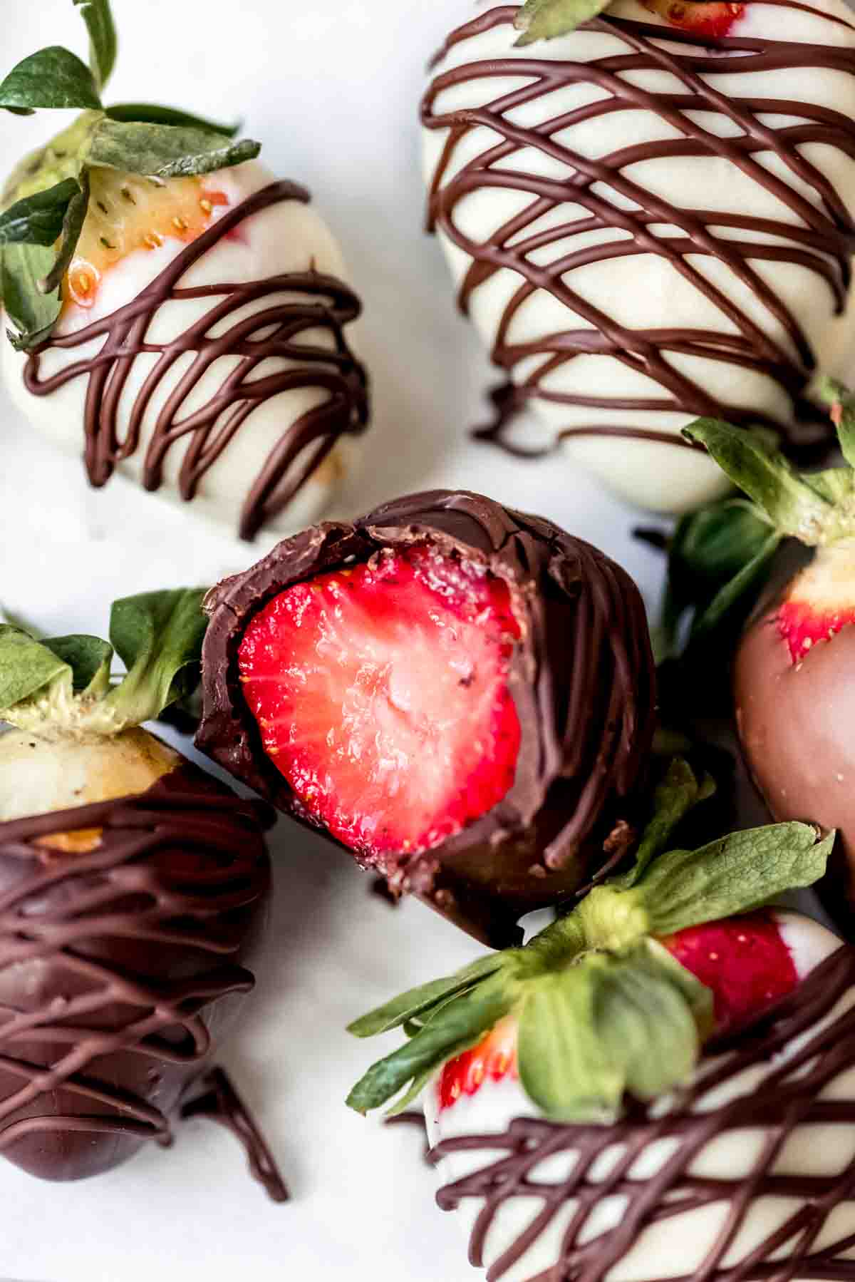 A chocolate covered strawberry with a bite taken out of it.