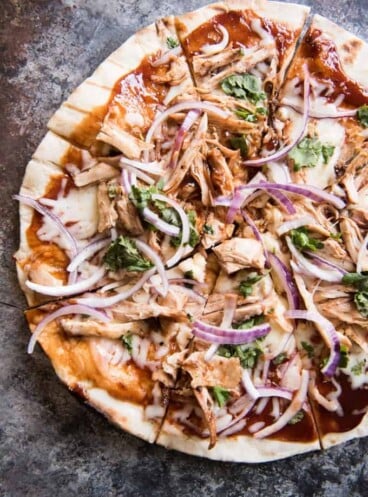 a sliced bbq chicken pizza with red onion, sauce, cheese and more