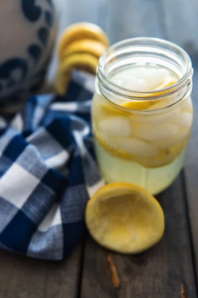 a mason jar with lemonade and ice next to a blue and white checkered towel