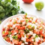 Authentic, fresh, Mexican Pico de Gallo, aka Salsa Fresca, is super easy to make and can be used in so many ways, from topping chicken or fish, adding to tacos, salads, and more, or just serving as a salsa with chips! We even eat it at breakfast! Even better, there is no cooking involved in making pico de gallo so it's especially good during the summer when it's too hot to cook much! You just chop up the tomatoes, onions, jalapeno, garlic, and cilantro, toss it with a little lime juice and a bit of salt, and you're good to go! Great for parties, Cinco de Mayo, tailgating, and so much more!