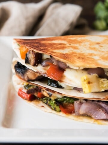 Grilled Summer Vegetable Quesadillas stacked on top of eachother on a white plate