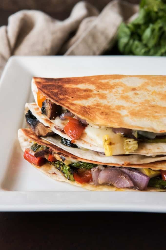 grilled summer vegetable quesadillas stacked on top of eachother on a white plate