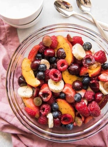 an aerial view of a summer fruit salad with poppyseed dressing in a glass bowl