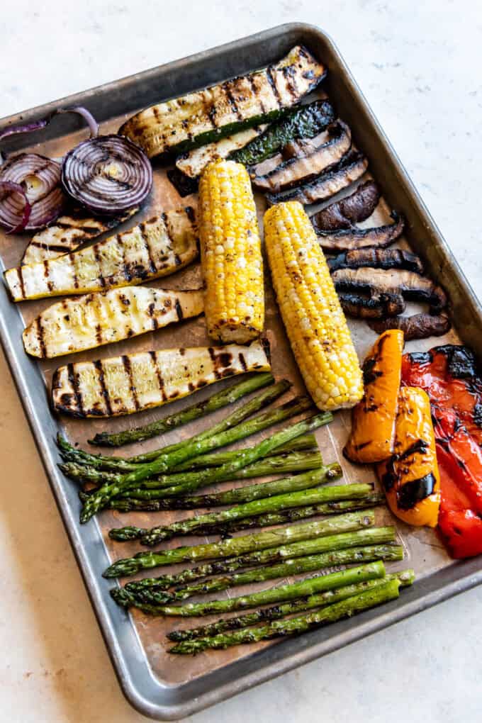 An overhead image of grilled vegetables on a baking sheet.