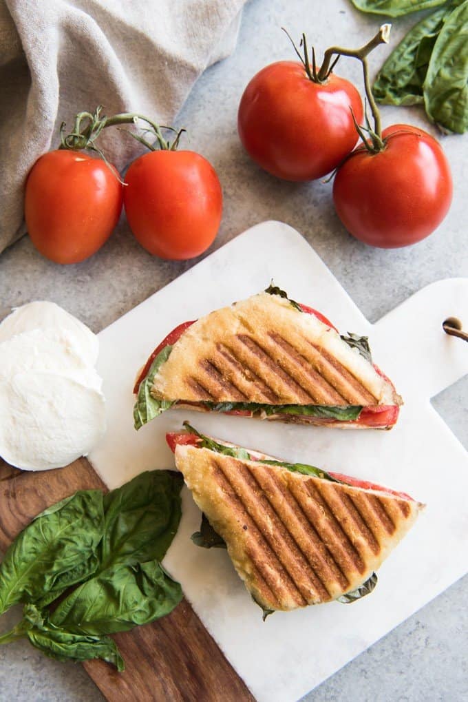 an aerial view of the grilllines on a caprese panini and more tomato cheese and basil around it