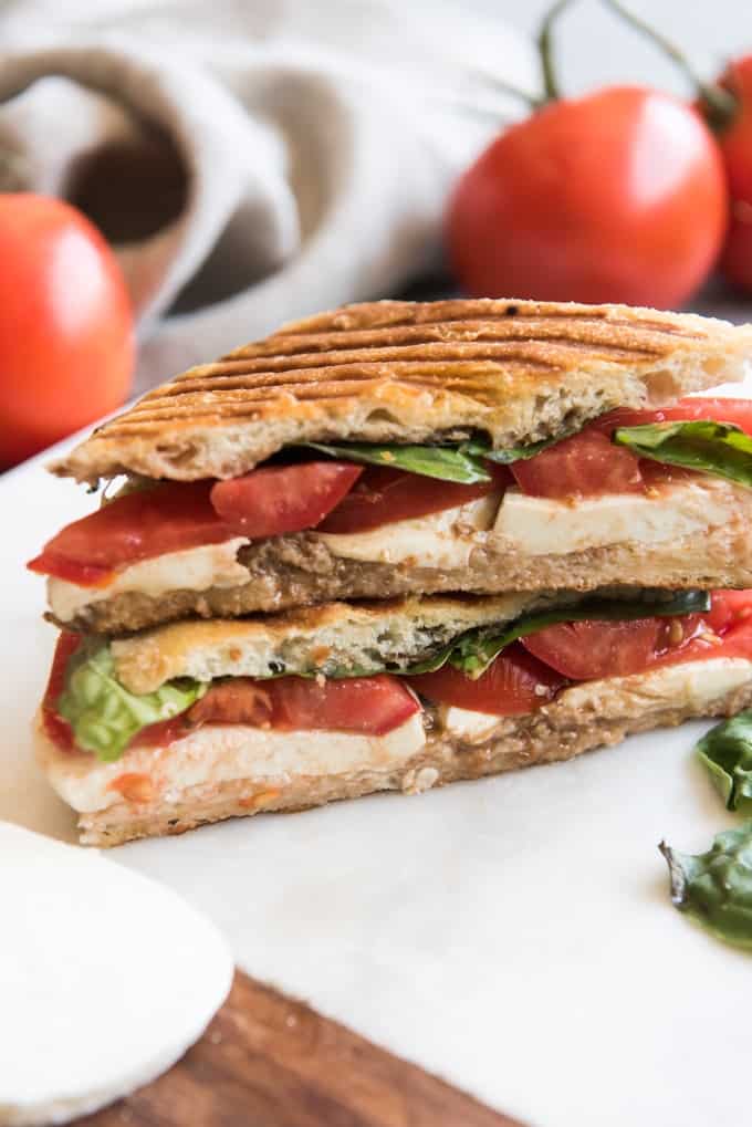 a stacked and sliced Grilled Caprese Panini on a cutting board