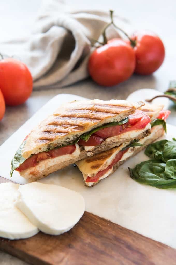 whole tomatoes behind a stacked caprese panini