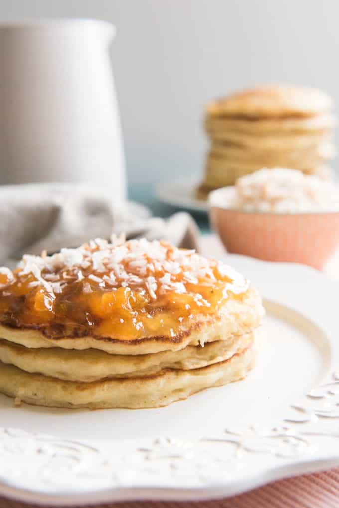a stack of toasted coconut pancakes on a white plate