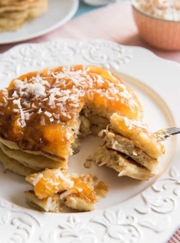 Toasted Coconut Pancakes with a few bites removed on a white plate