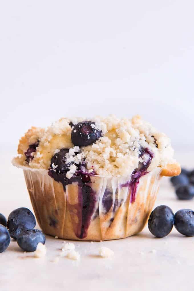 a blueberry streusel muffin with fresh blueberries around it