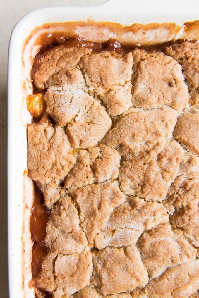 a corner of the baking dish filled with fresh peach cobbler