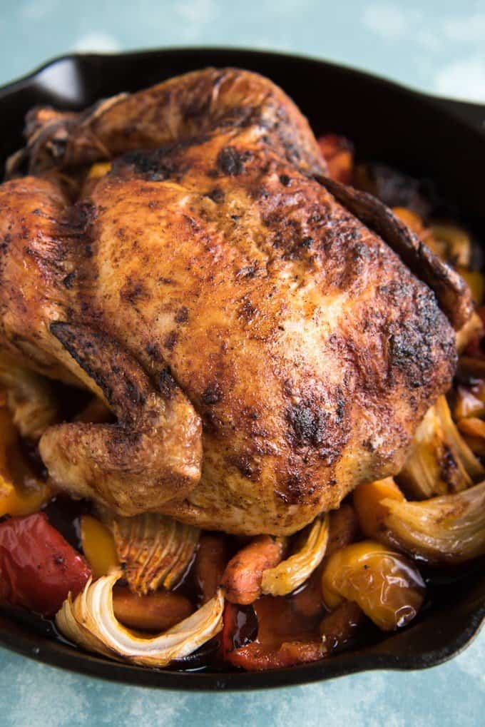 roasted chicken on veggies in a cast iron skillet
