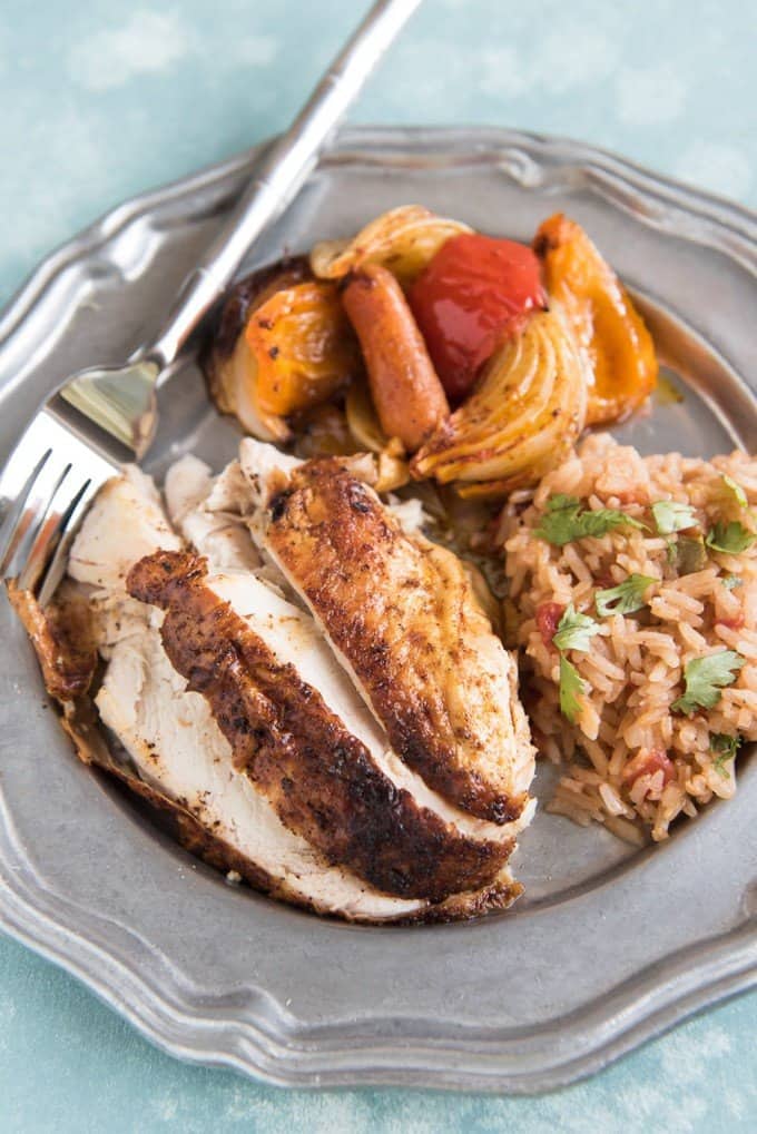 roasted chicken veggies and rice on a plate with a fork