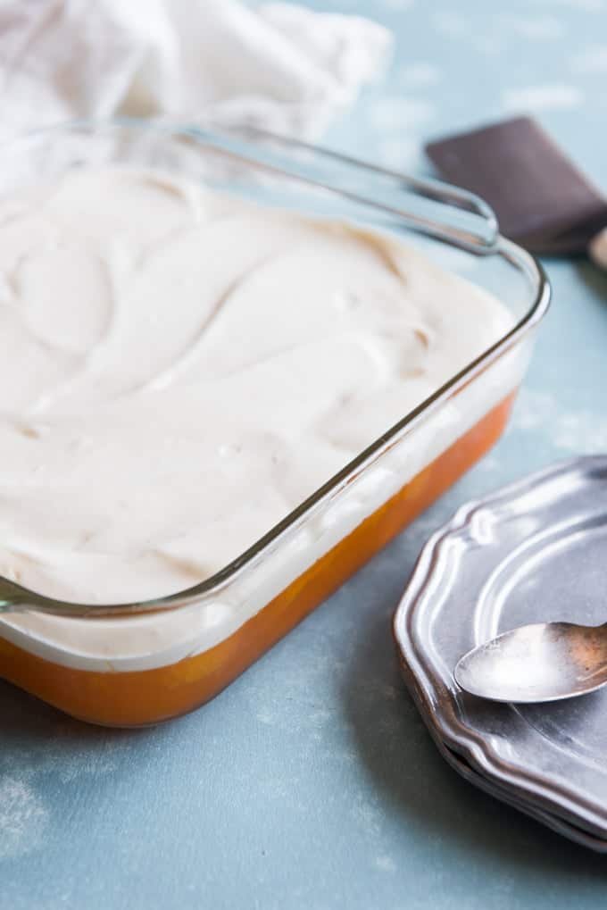 whipped cream topped orange jello salad in a baking dish
