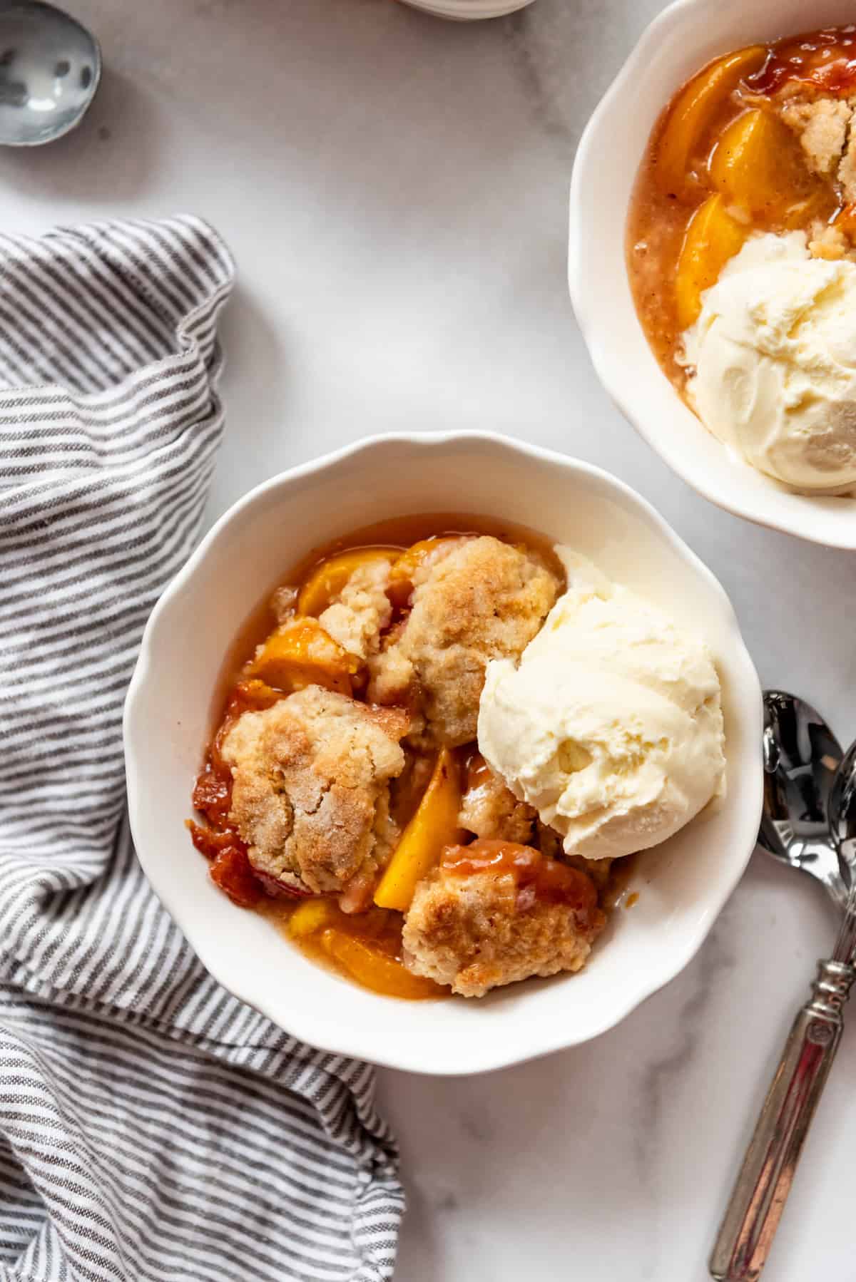 An image of a bowl of peach cobbler with ice cream.