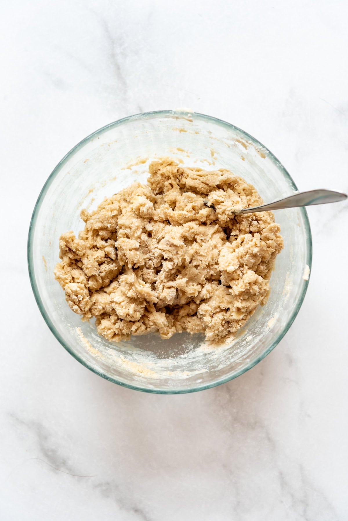 Adding wet ingredients to dry ingredients to make cobbler topping in a bowl.