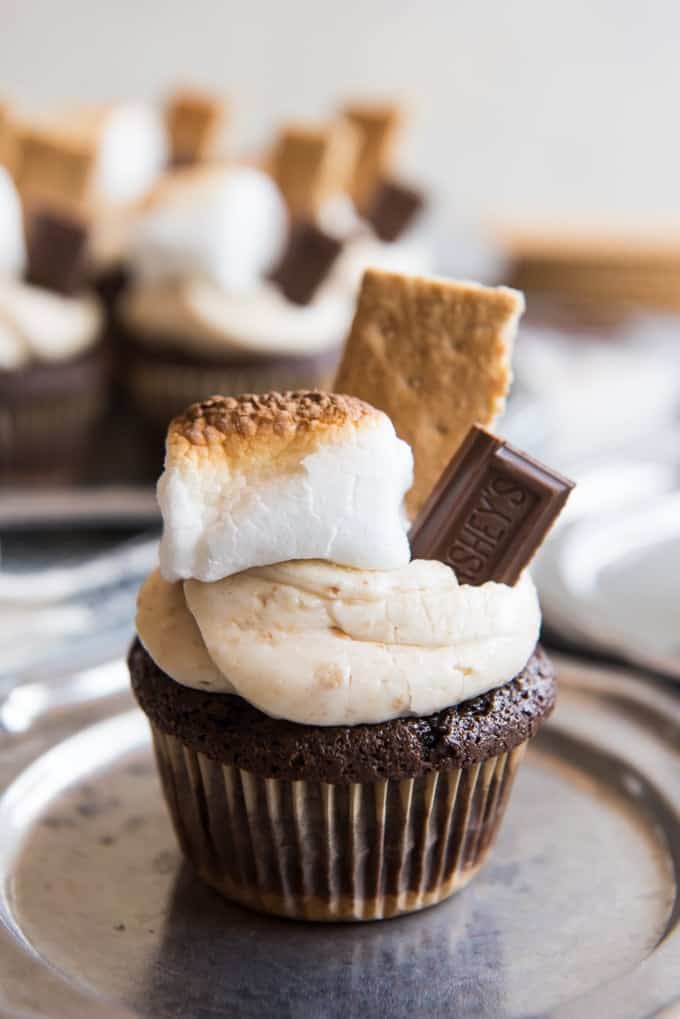 chocolate cupcake topped with graham cracker frosting and garnished with toasted marshmallow, graham cracker and chocolate pieces