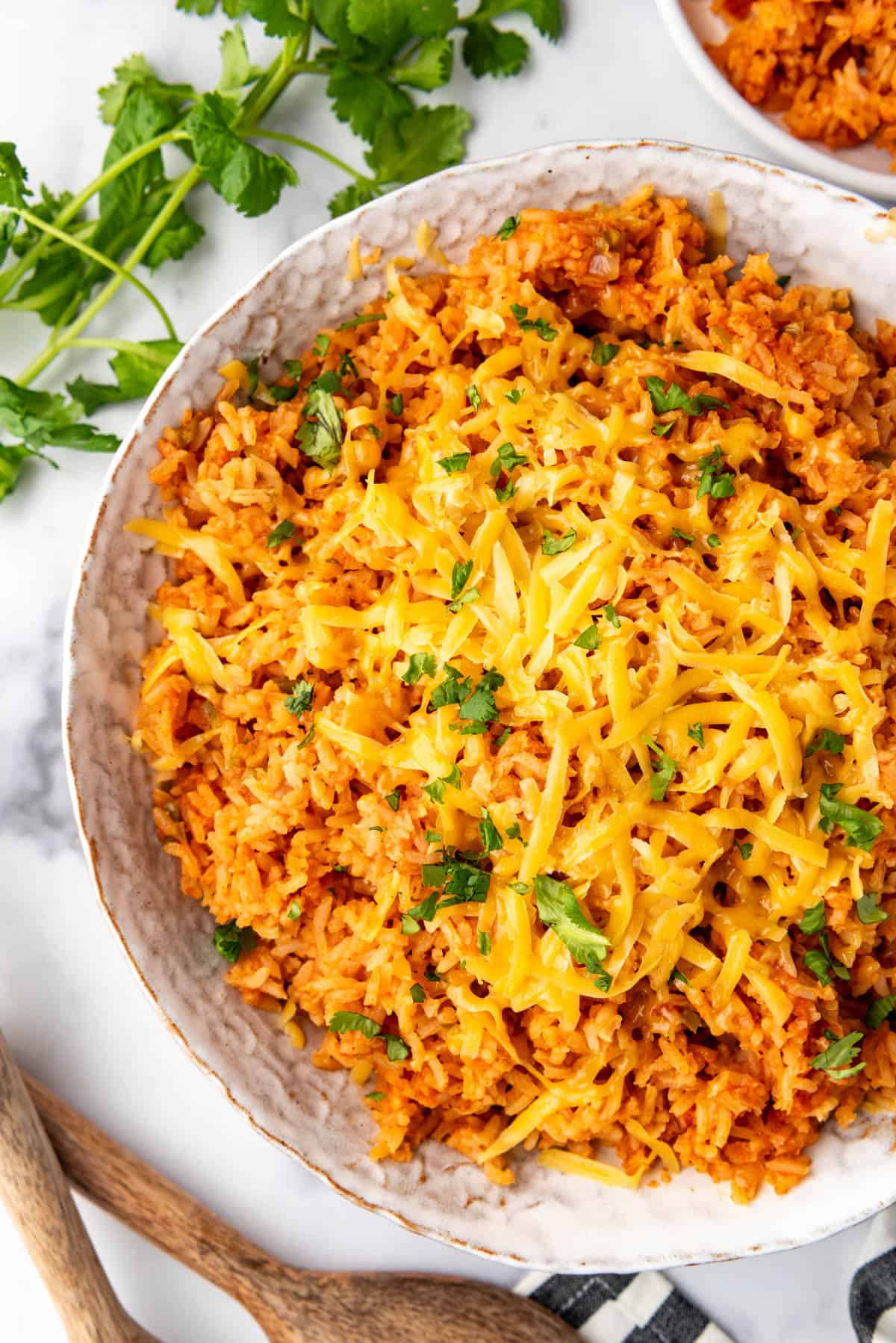 An overhead image of a large dish of Mexican rice topped with shredded cheddar cheese.