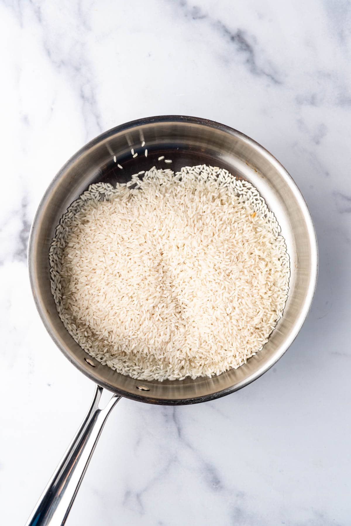 Toasting long grain white rice in a pan with oil.