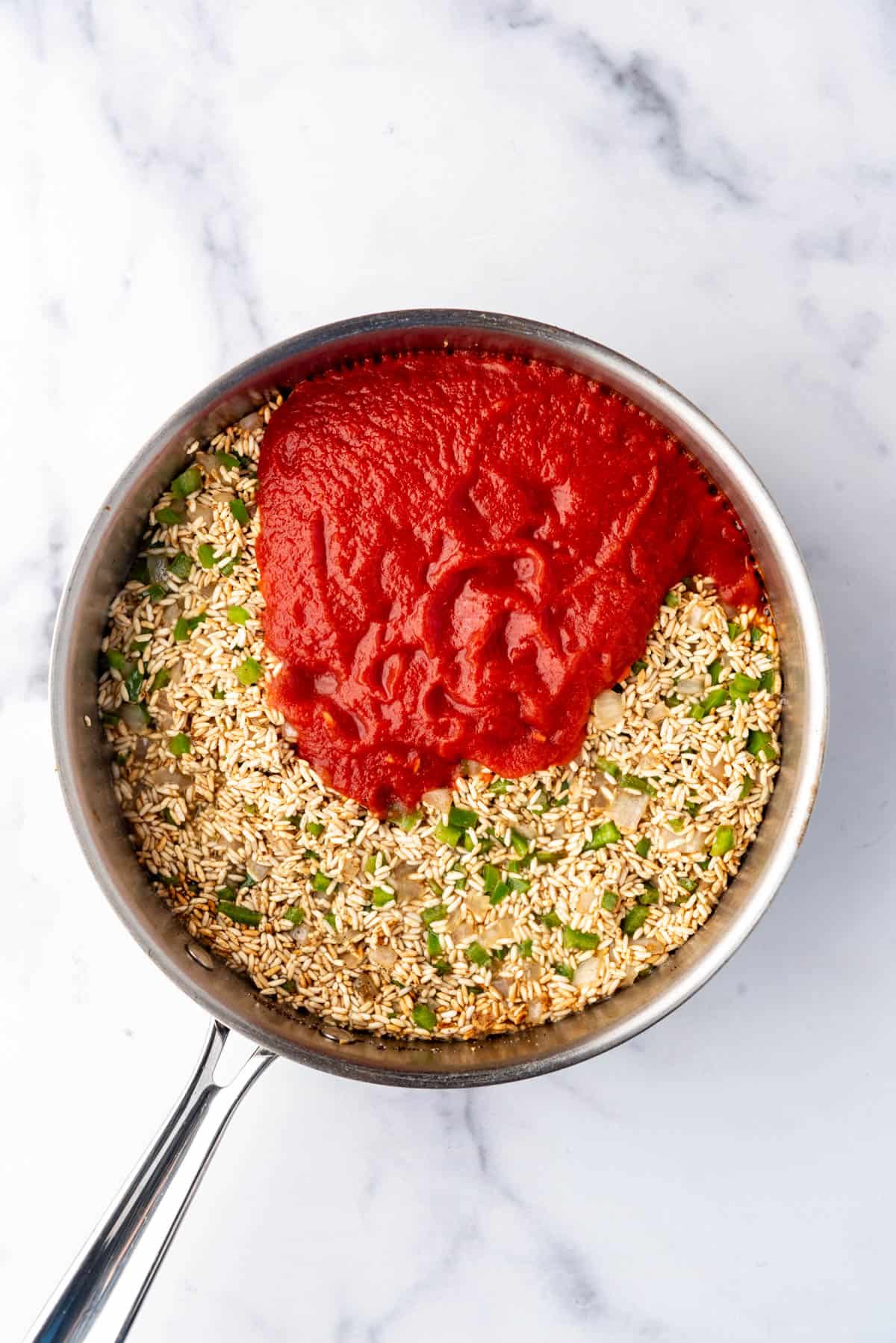 Adding tomato sauce to a pan of rice.