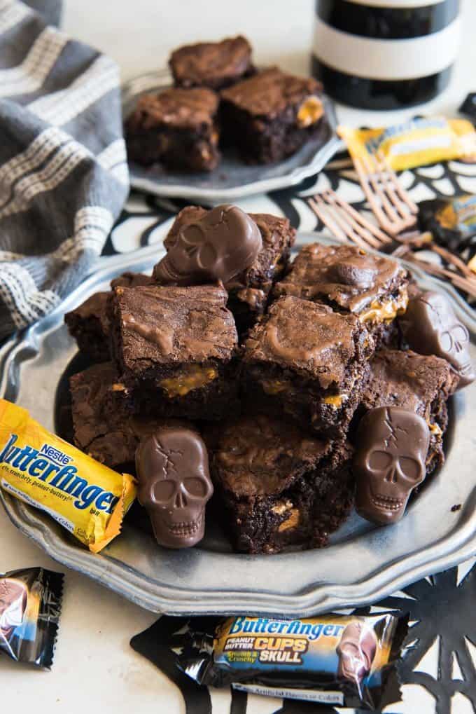 piles of stacked butterfinger brownies on a plate with halloween butterfinger candies