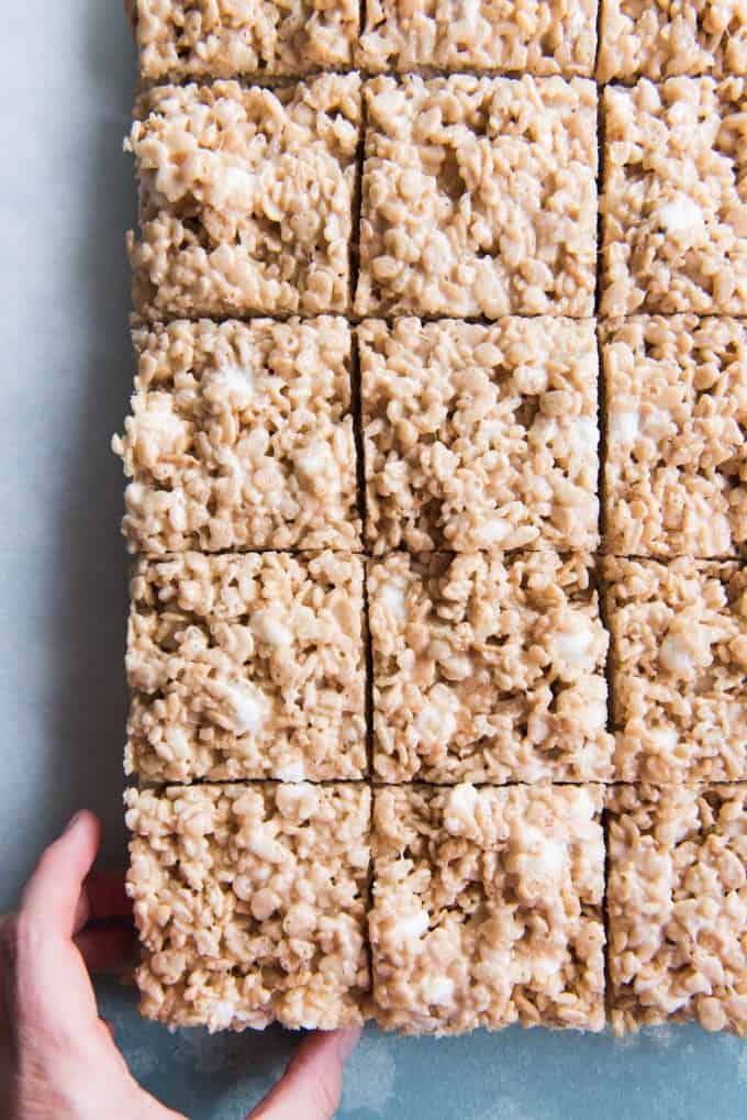 An image of a hand reaching for a salted brown butter rice krispie treat square.