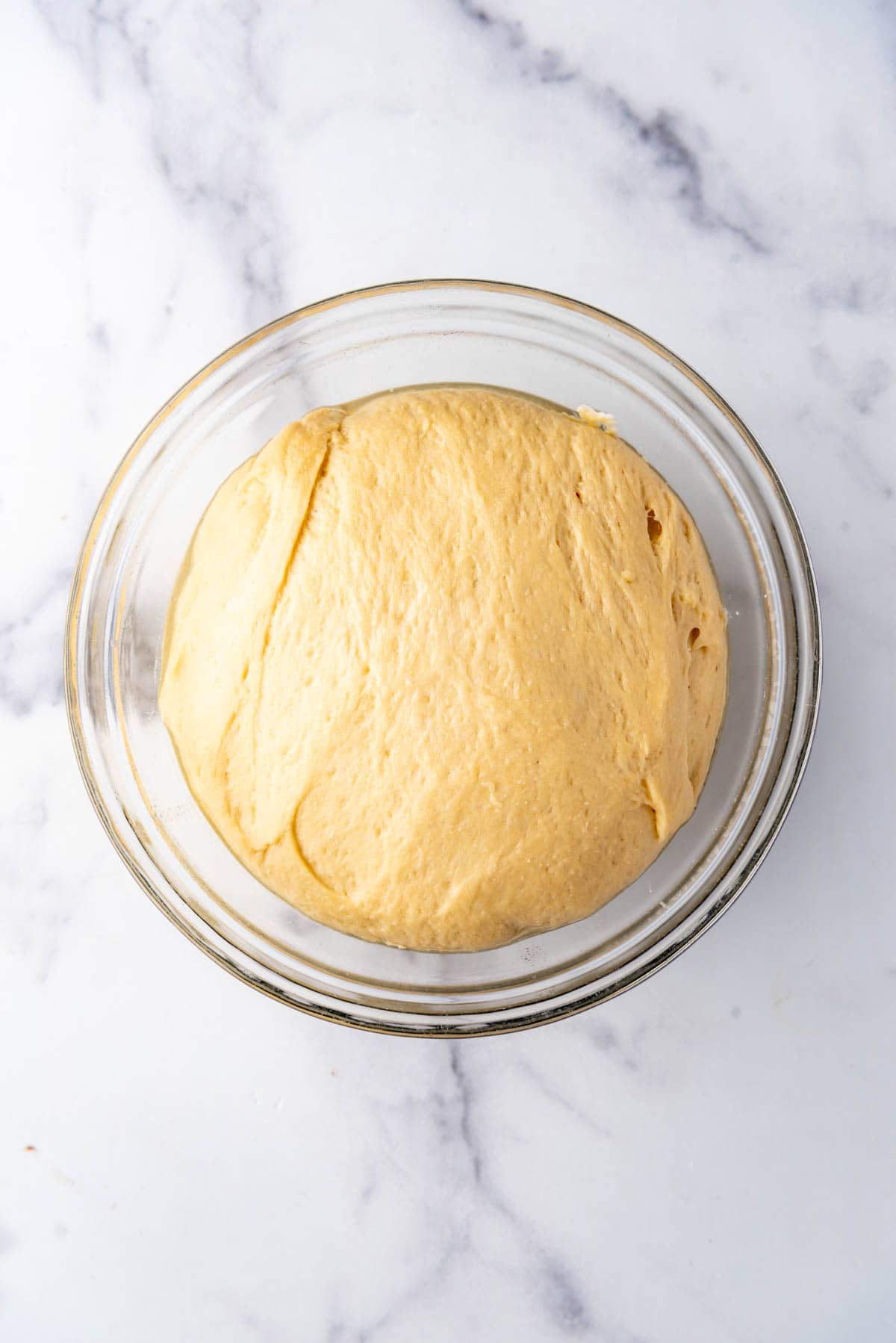 Risen bread dough in a glass dish.