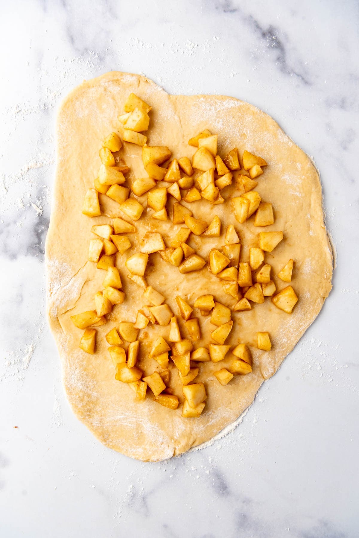 Spreading apple filling over bread dough.