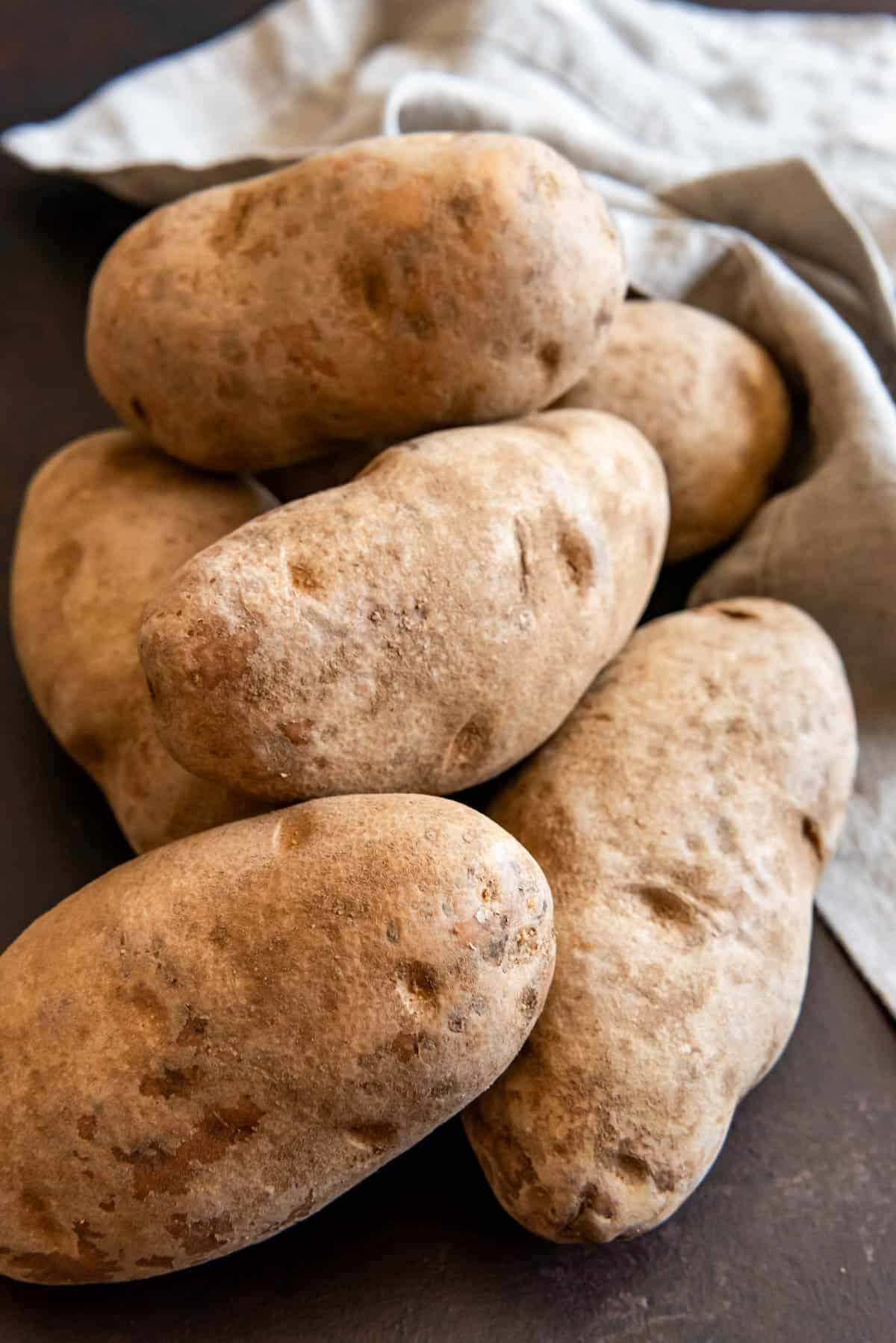 A pile of unwashed russet potatoes to be used for baked potatoes.