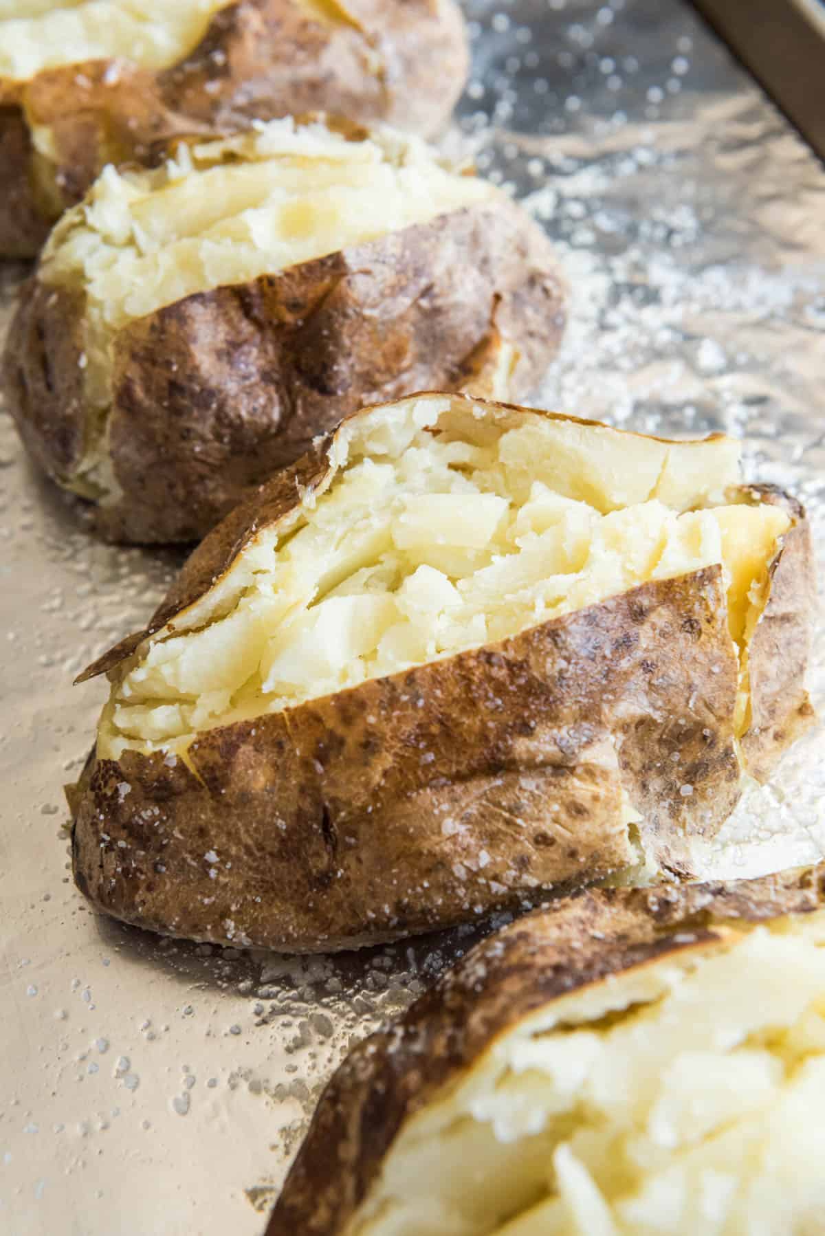 Split open baked potatoes on baking sheet.