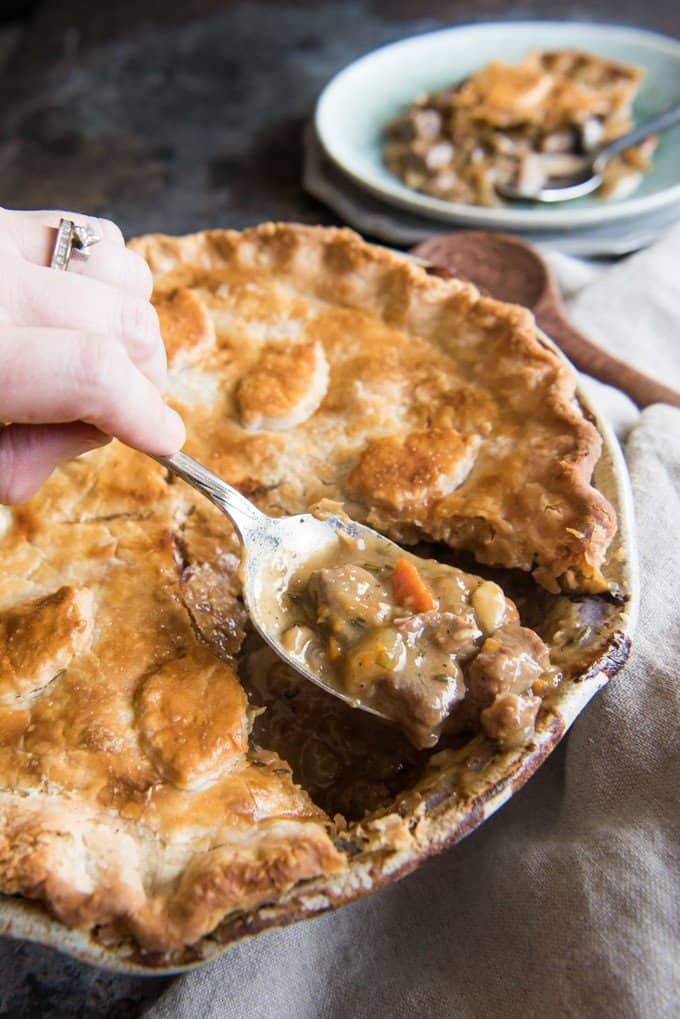a spoon holding up some filling from the inside of a beef steak pie