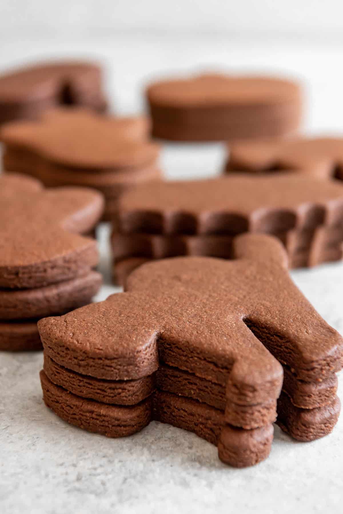 Stacks of chocolate cut out cookies in Halloween shapes.