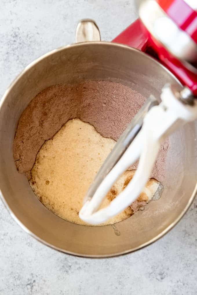 An image of flour, cocoa powder, sugar, eggs, and buttermilk being mixed together in a stand mixer.