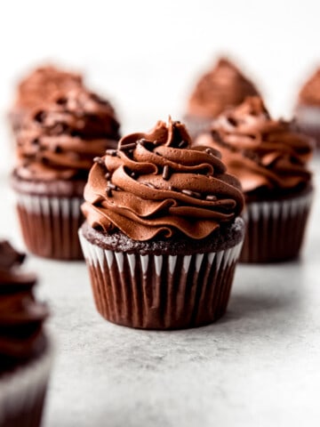 An image of homemade chocolate cupcakes with chocolate frosting and chocolate sprinkles.