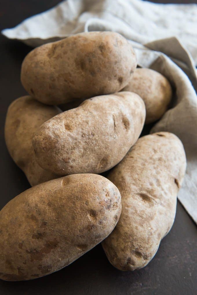 A pile of unwashed russet potatoes to be used for baked potatoes.