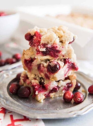 stacked cranberry shortcake bars brsting with cranberries and berries beside it