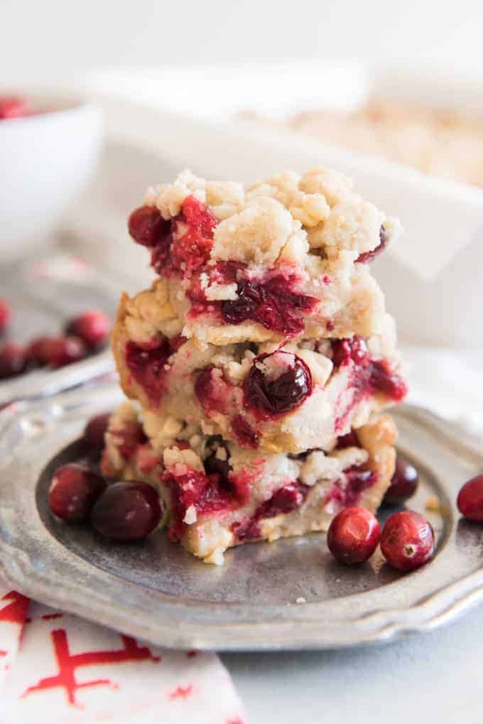stacked cranberry shortcake bars brsting with cranberries and berries beside it