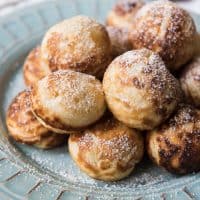 Aebleskivers on a plate topped with a light dusting of powdered sugar