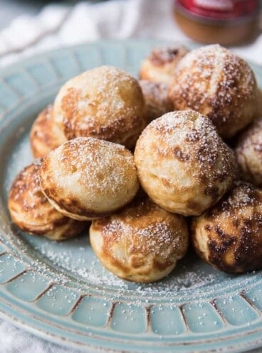 Aebleskivers on a plate topped with a light dusting of powdered sugar