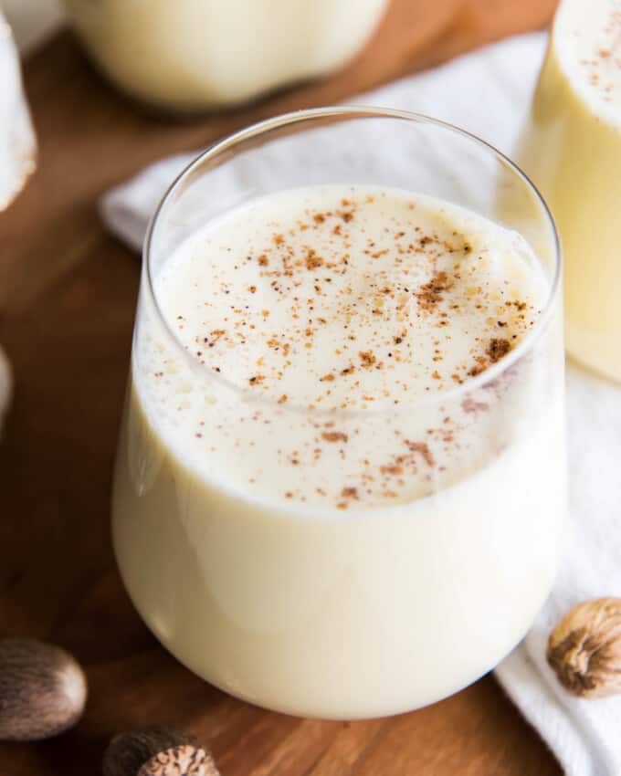 An overhead image of a glass of homemade eggnog with freshly grated nutmeg sprinkled on top.