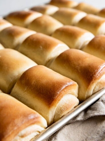 Tray of freshly baked rolls fresh from the oven, with buttered tops.