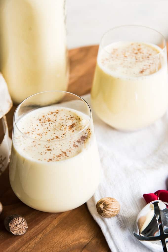 Eggnog in glasses next to nuts and a bell